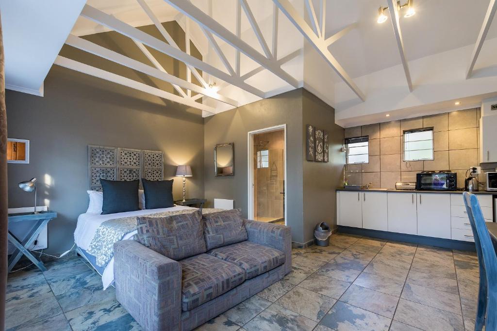 a bedroom with a bed and a couch and a kitchen at Silverstone Guesthouse in Johannesburg
