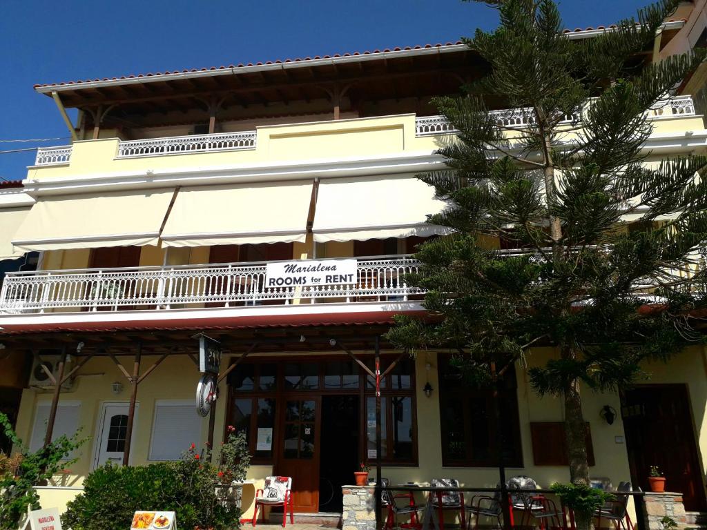 a building with a balcony and tables and chairs at Marialena Pension in Ireon