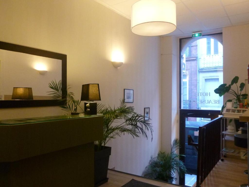 a waiting room with a mirror and some plants at Hotel Beauséjour in Toulouse