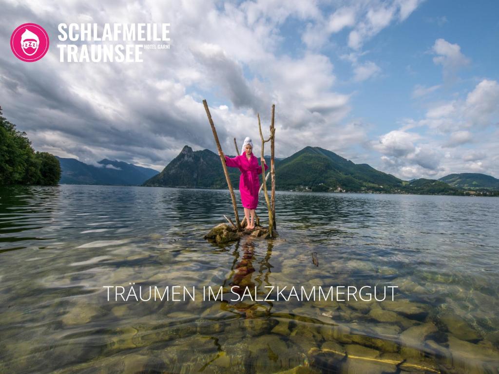 a woman standing on a stand up paddle board in the water at Schlafmeile Traunsee in Ebensee