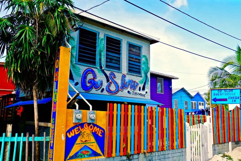a colorful house with a fence in front of it at Go Slow Guesthouse in Caye Caulker