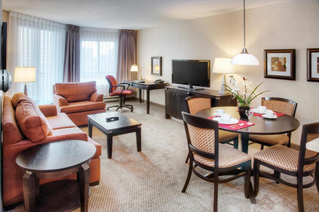 a living room filled with furniture and a tv at Les Suites Hotel in Ottawa