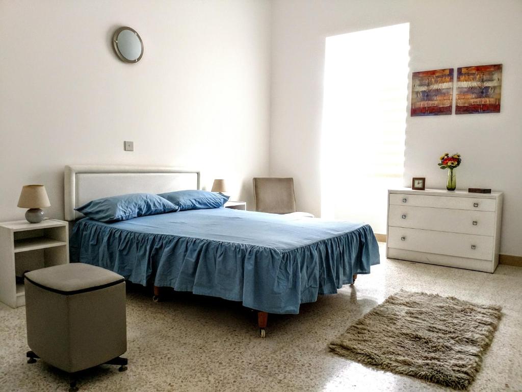 a bedroom with a blue bed and a dresser and a window at Charming Rooms with a Seaview in Sliema