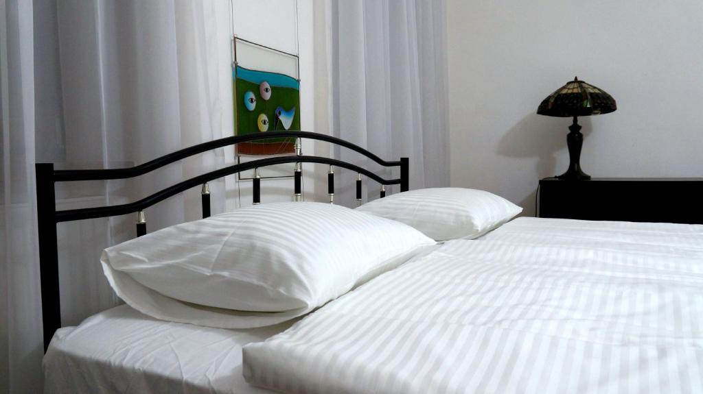 Una cama con sábanas blancas y almohadas en un dormitorio en U Salonu VIRGINIA, en Česká Kamenice