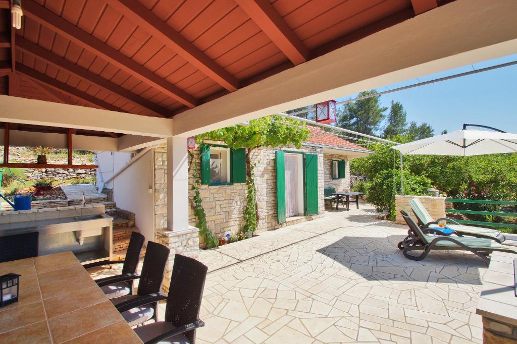 un patio con mesa, sillas y sombrilla en Holiday Home Liberan, en Vela Luka