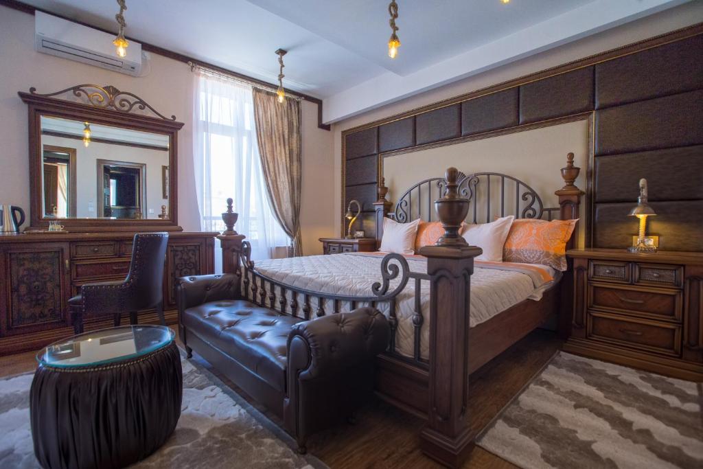 1 dormitorio con cama, silla y espejo en Robevski luxury rooms, en Bitola