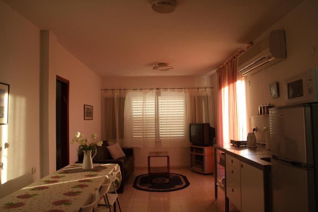 cocina y sala de estar con mesa y nevera en Kinneret Guesthouse, en Neot Golan