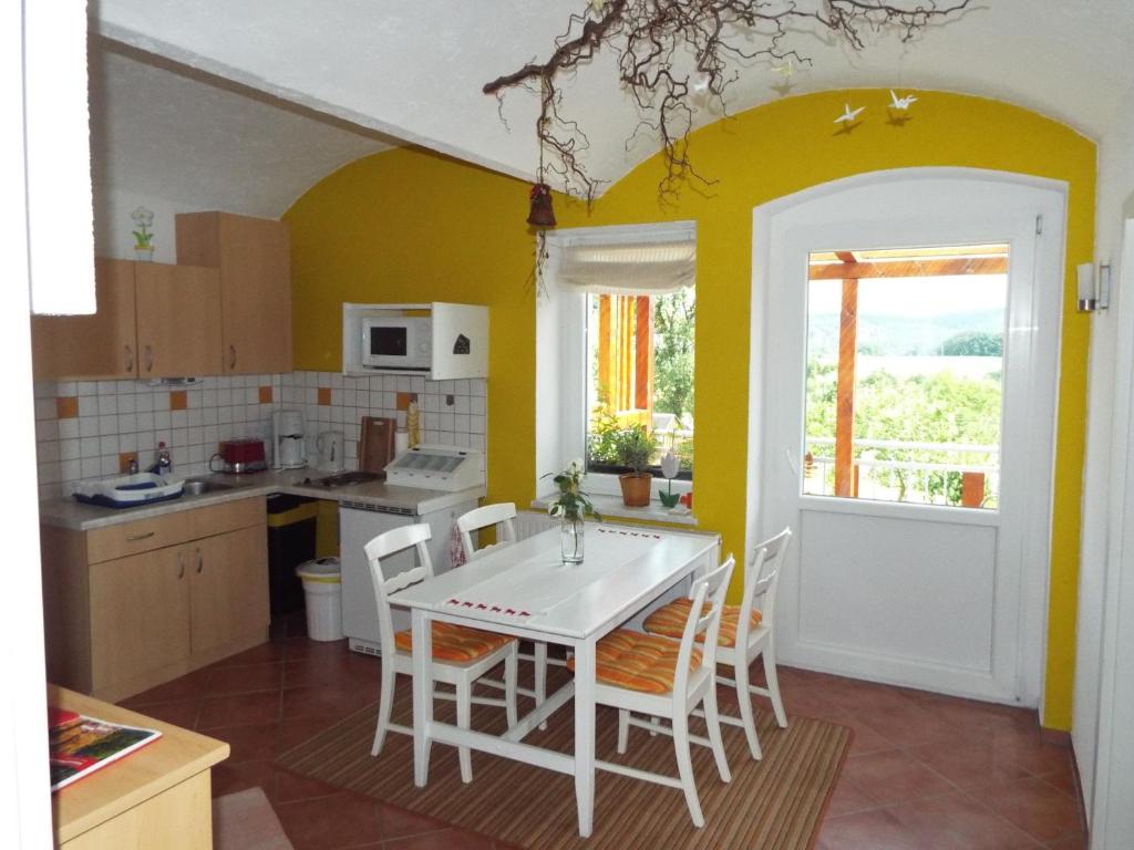 cocina con paredes amarillas, mesa blanca y sillas en Ferienwohnung Lindemann, en Weißig