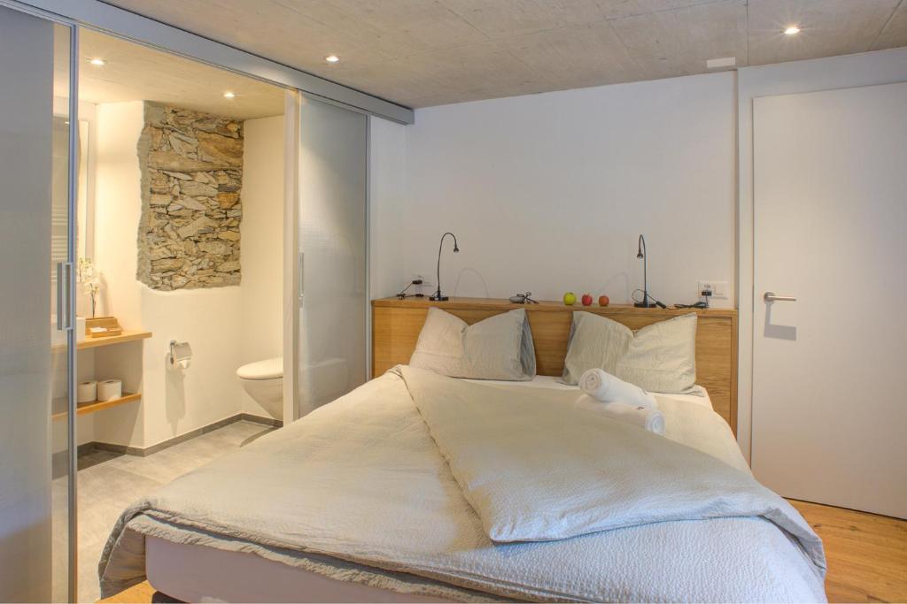 a bedroom with a large bed with white sheets at MyVerzasca Resort Ai piee in Brione