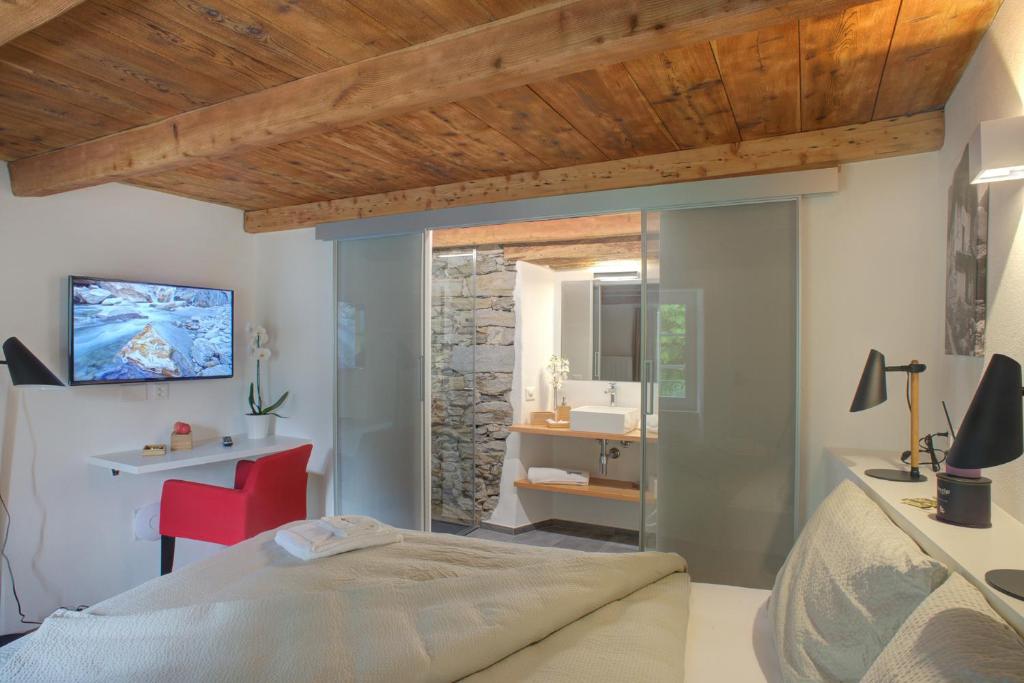 1 dormitorio con 1 cama y baño en MyVerzasca Resort Ai piee en Brione
