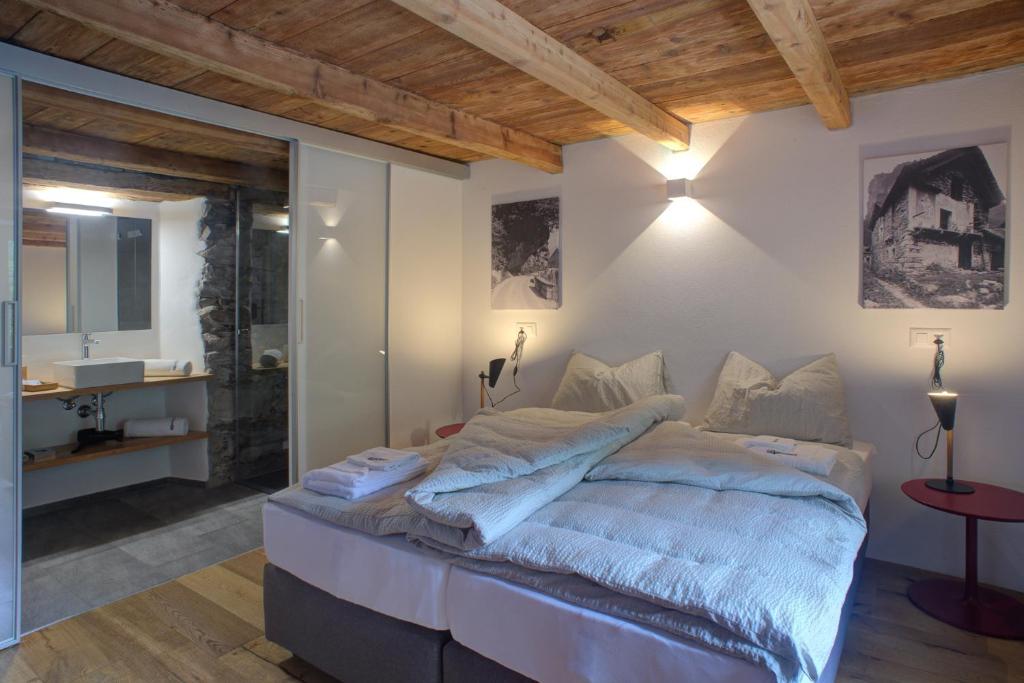 a bedroom with a large bed and a bathroom at MyVerzasca Resort Ai piee in Brione