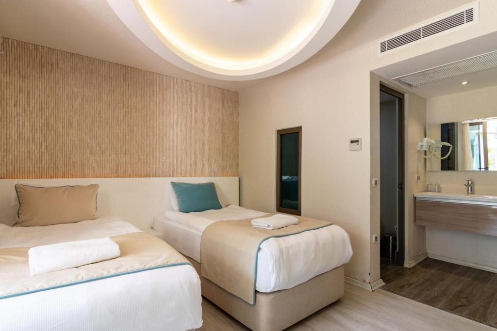 two beds in a room with a sink at The D Hotel Çeşme Resort in Çeşme