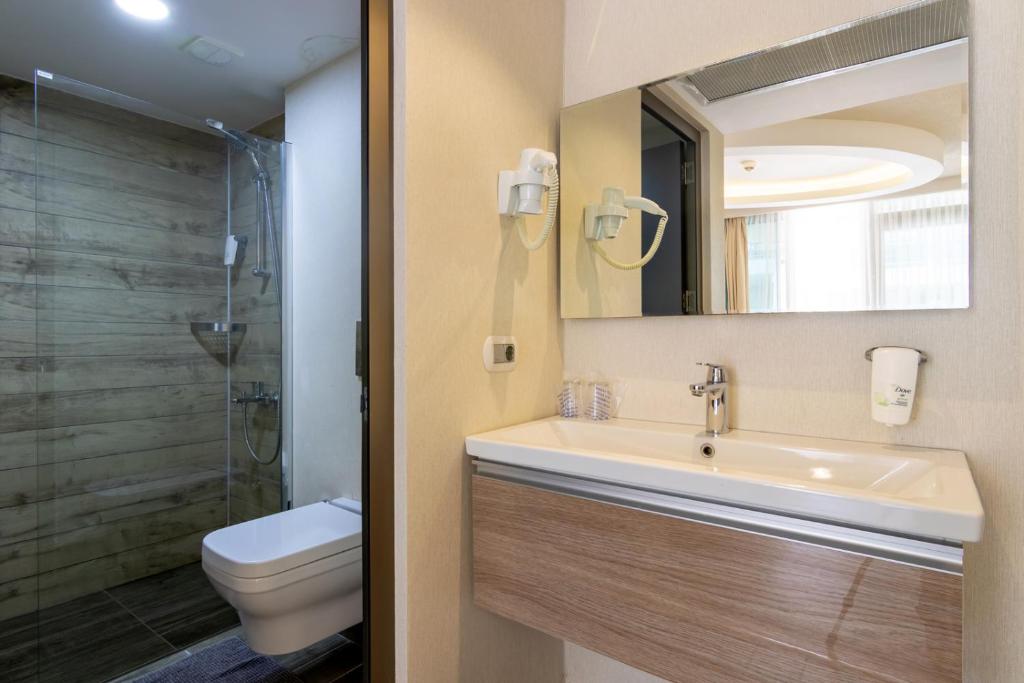 a bathroom with a sink and a toilet and a mirror at The D Hotel Çeşme Resort in Çeşme