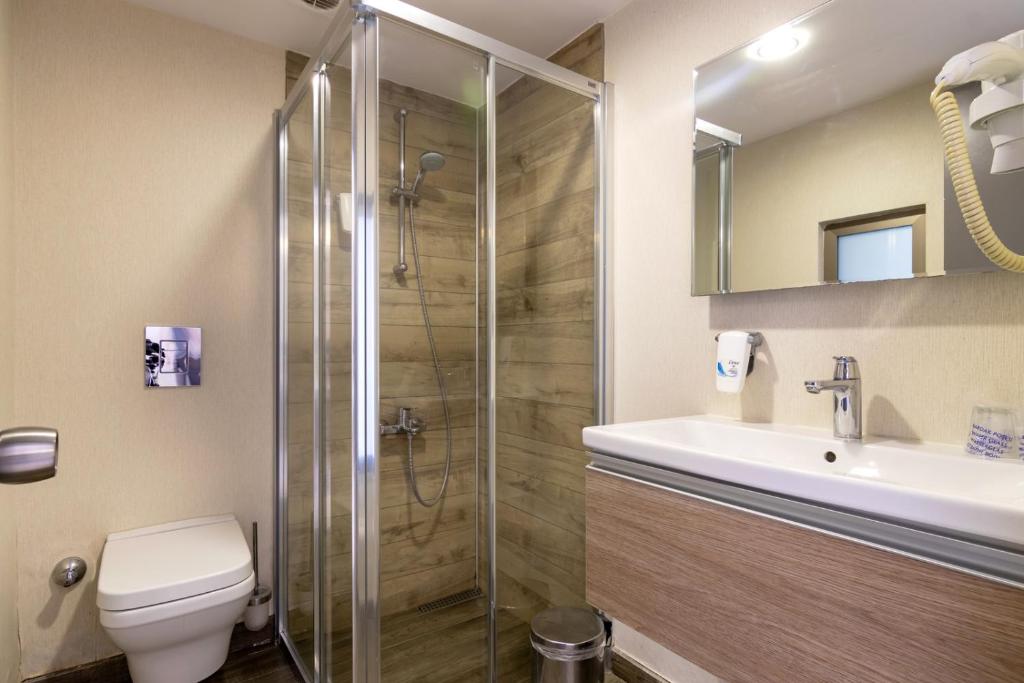 a bathroom with a shower and a toilet and a sink at The D Hotel Çeşme Resort in Çeşme