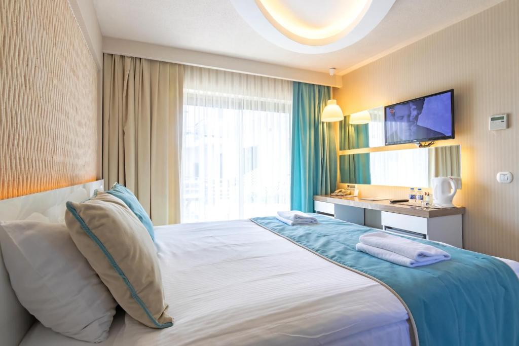 a hotel room with a large bed and a television at The D Hotel Çeşme Resort in Çeşme