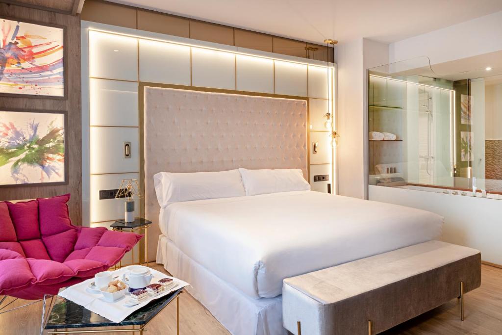 a bedroom with a large white bed and a chair at Barceló Ourense in Ourense