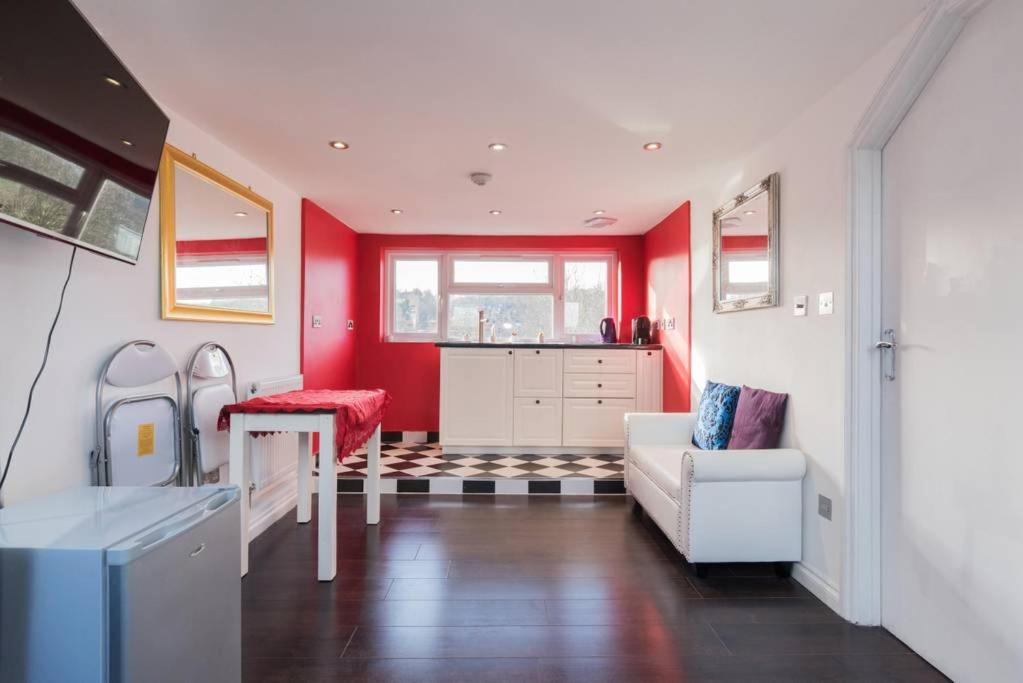 een woonkamer met rode muren en een bank en een tafel bij Studio flat 15 min from Greenwich ( en-suite) in Plumstead