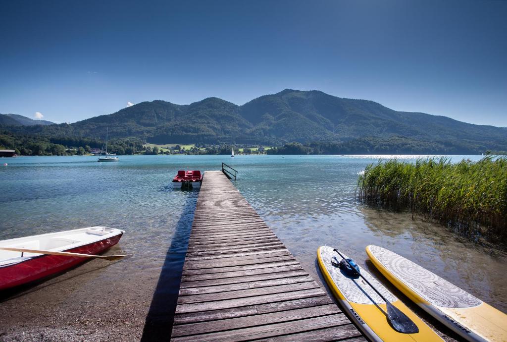 a wooden dock with two kayaks on the water at Hotel Seewinkel in Fuschl am See
