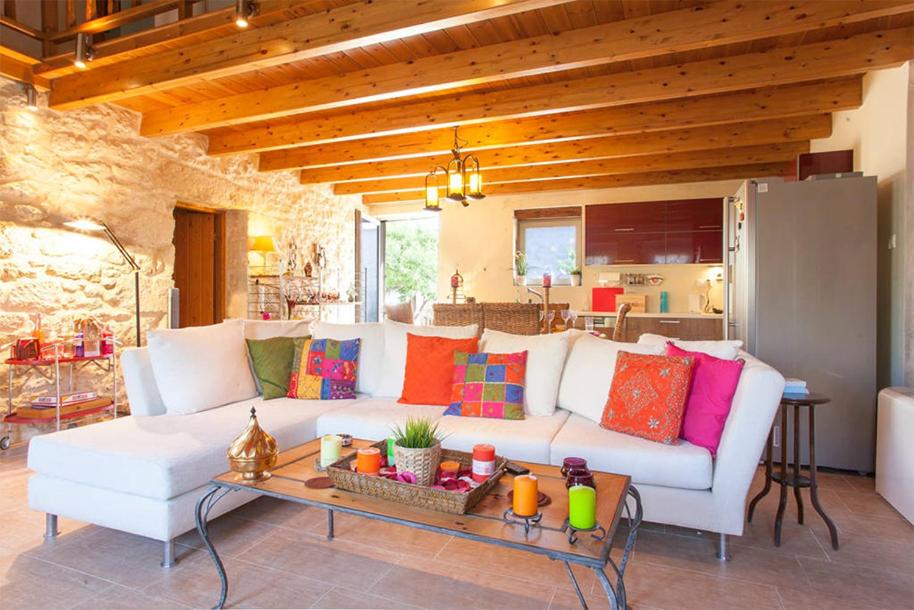 sala de estar con sofá blanco y almohadas coloridas en Old Stone House, en Archanes
