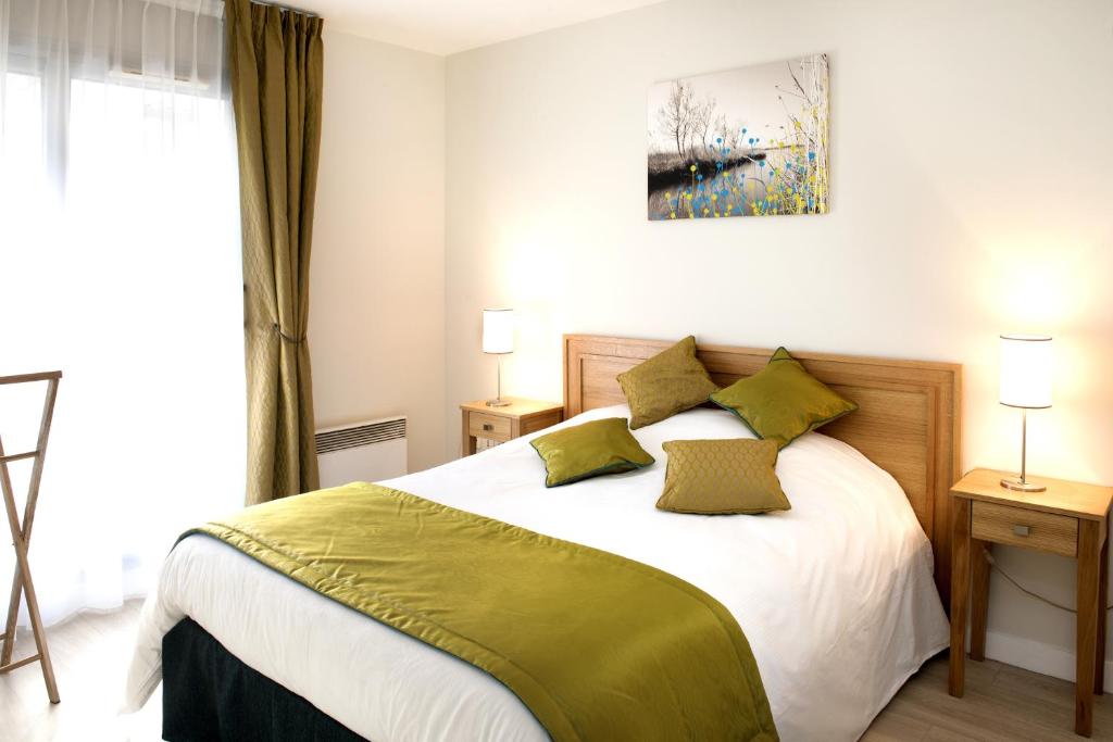 a bedroom with a large white bed with green pillows at Domitys Paris Plaisance in Paris