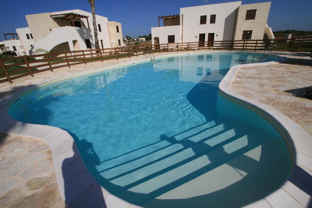 a swimming pool in front of a house at Le Casuzze del Residence Lido Burrone in Favignana