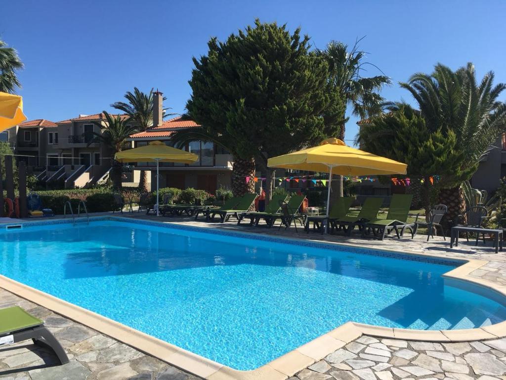 una gran piscina con sillas y sombrillas en Ariadnes Holiday Accommodation I, en Apidias Lakos