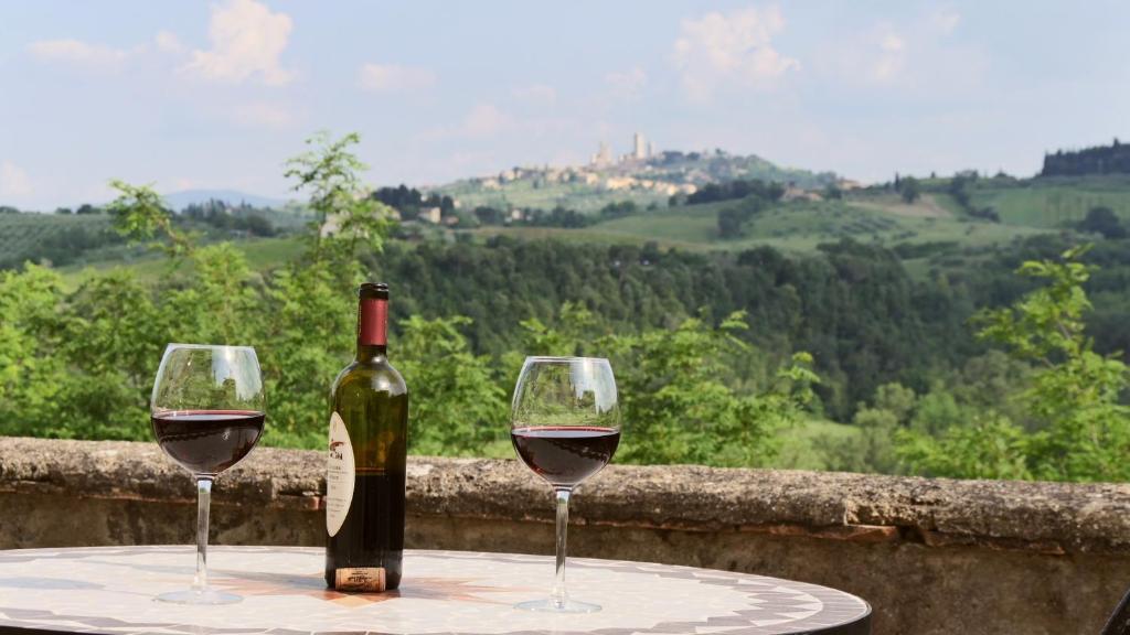 eine Flasche Wein und zwei Gläser auf dem Tisch in der Unterkunft The Best View San Gimignano Apartments in San Gimignano