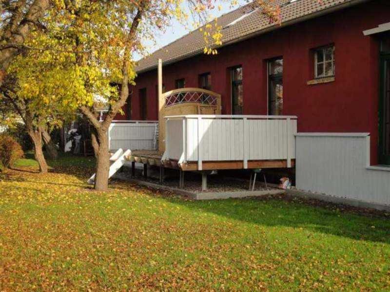 una casa roja con un banco frente a un patio en Ferienwohnungen am Museumshafen en Greifswald