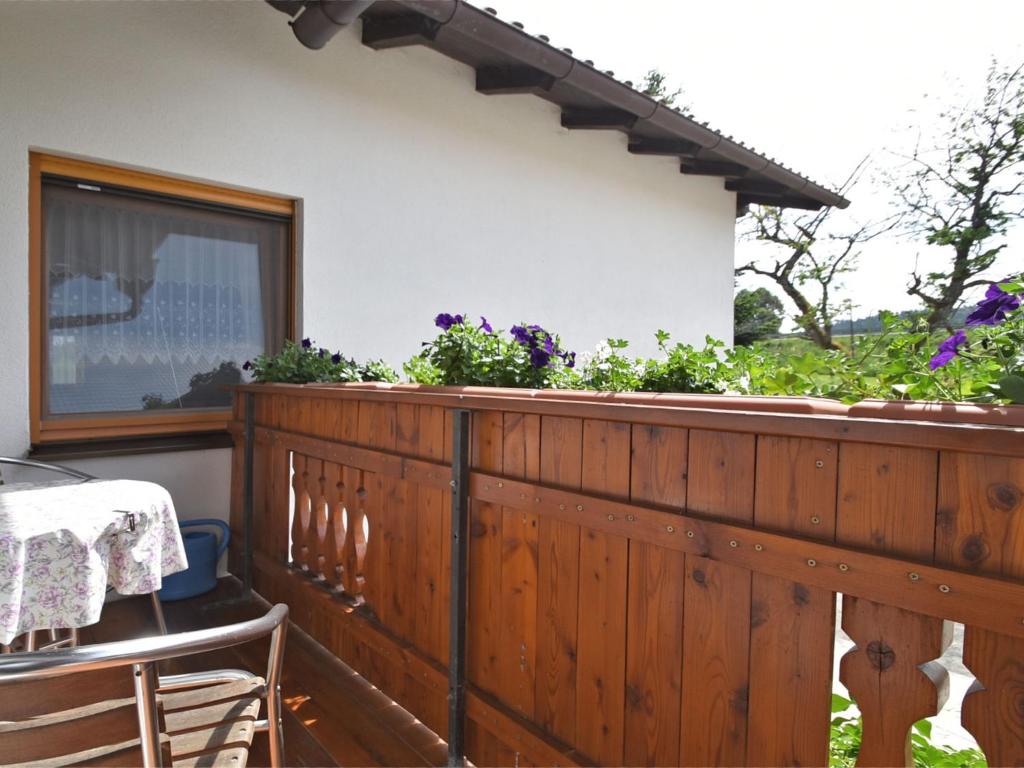 a balcony with a wooden fence and a table and chairs at Small cosy apartment in the Bavarian Forest in a familiar atmosphere in Sonnen