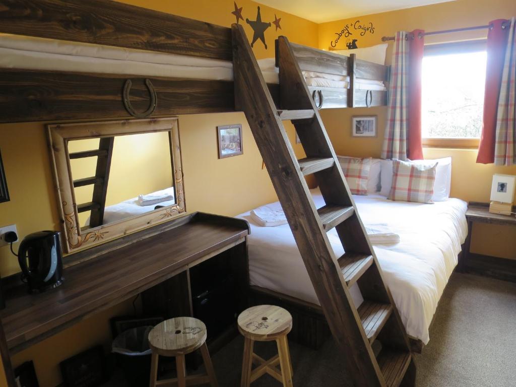a bedroom with a bunk bed with a mirror and two stools at Adventurer's Village Milton Keynes in Milton Keynes