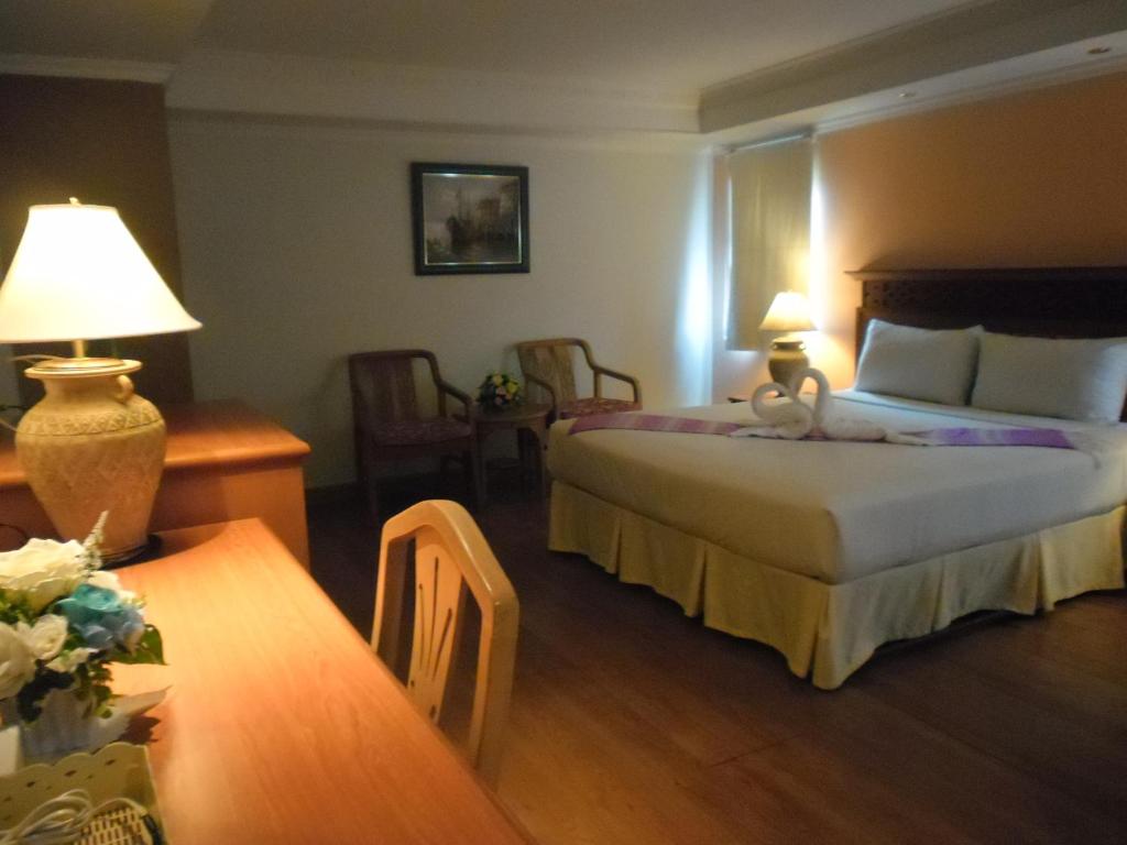 a hotel room with two beds and a table and chairs at Hatyai Paradise Hotel & Resort in Hat Yai