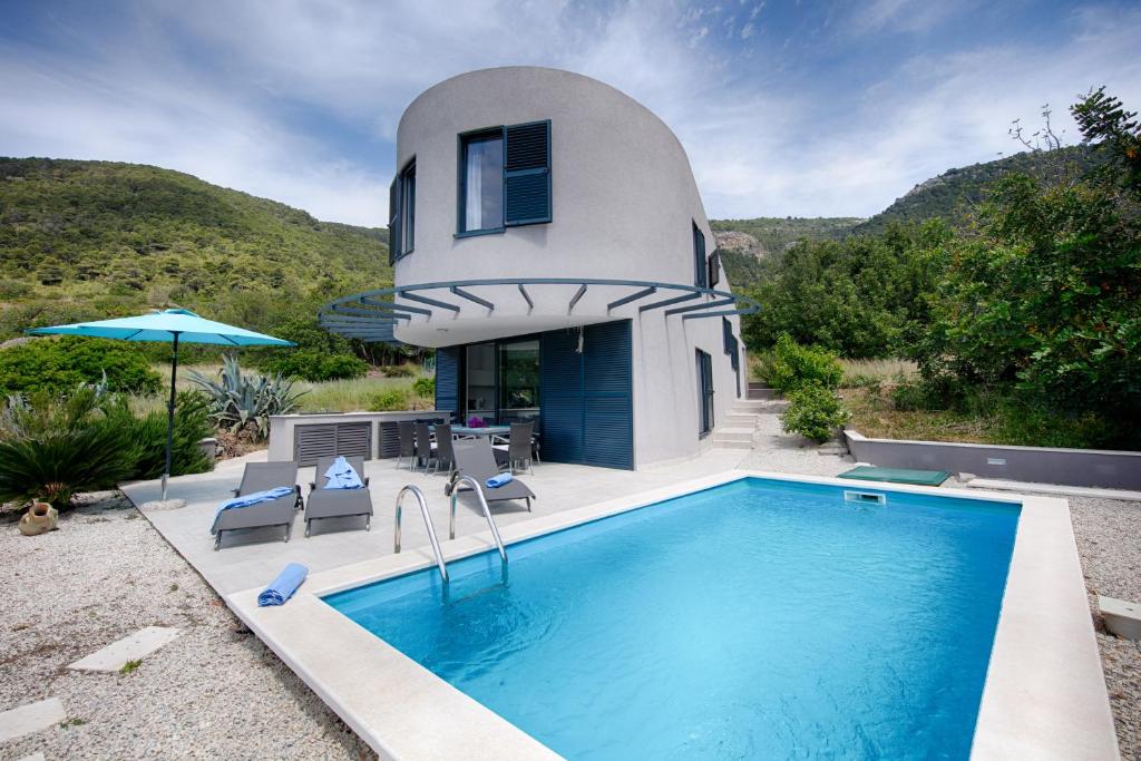 una casa con piscina frente a ella en Villa Periska Komiža, en Komiža