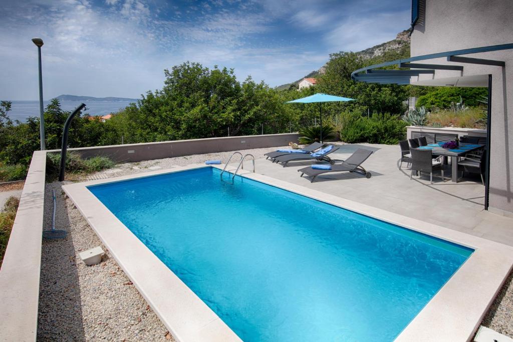 a swimming pool with a table and chairs next to a house at Villa Periska Komiža in Komiža