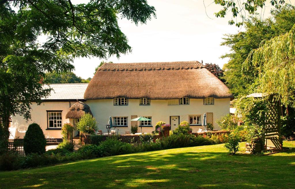 een groot wit huis met een rieten dak bij The Barn and Pinn Cottage in Sidmouth