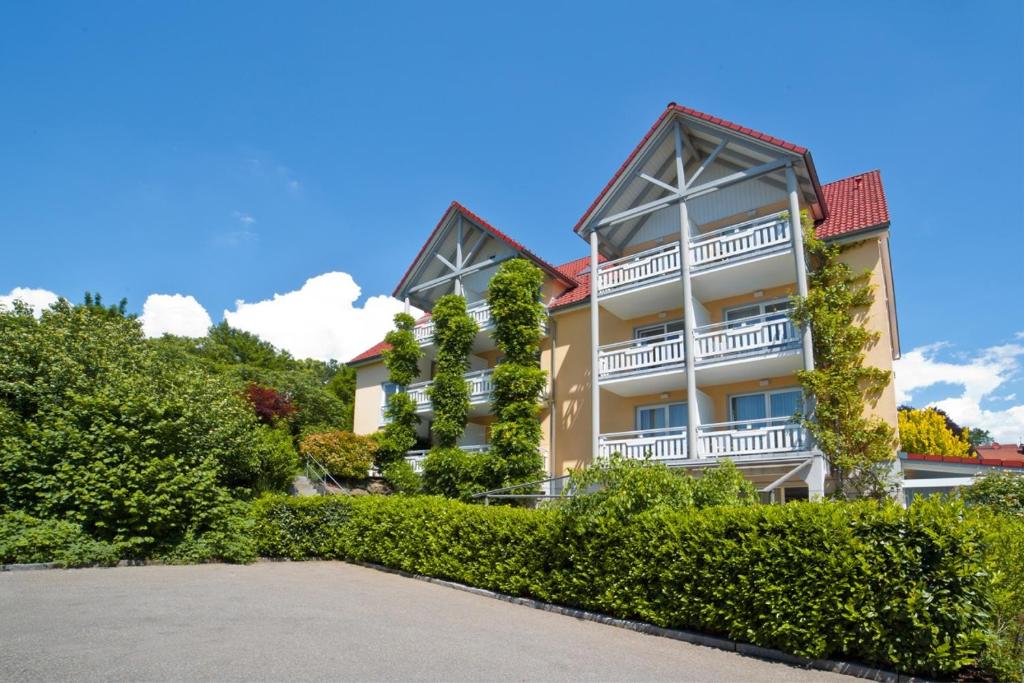 um grande edifício de apartamentos com varandas e arbustos em allgovia hotel garni em Wangen im Allgäu