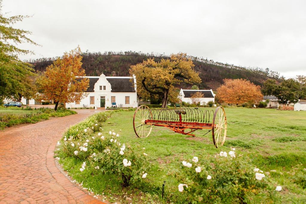a red bench sitting in the grass in front of a house at Basse Provence Country House in Franschhoek