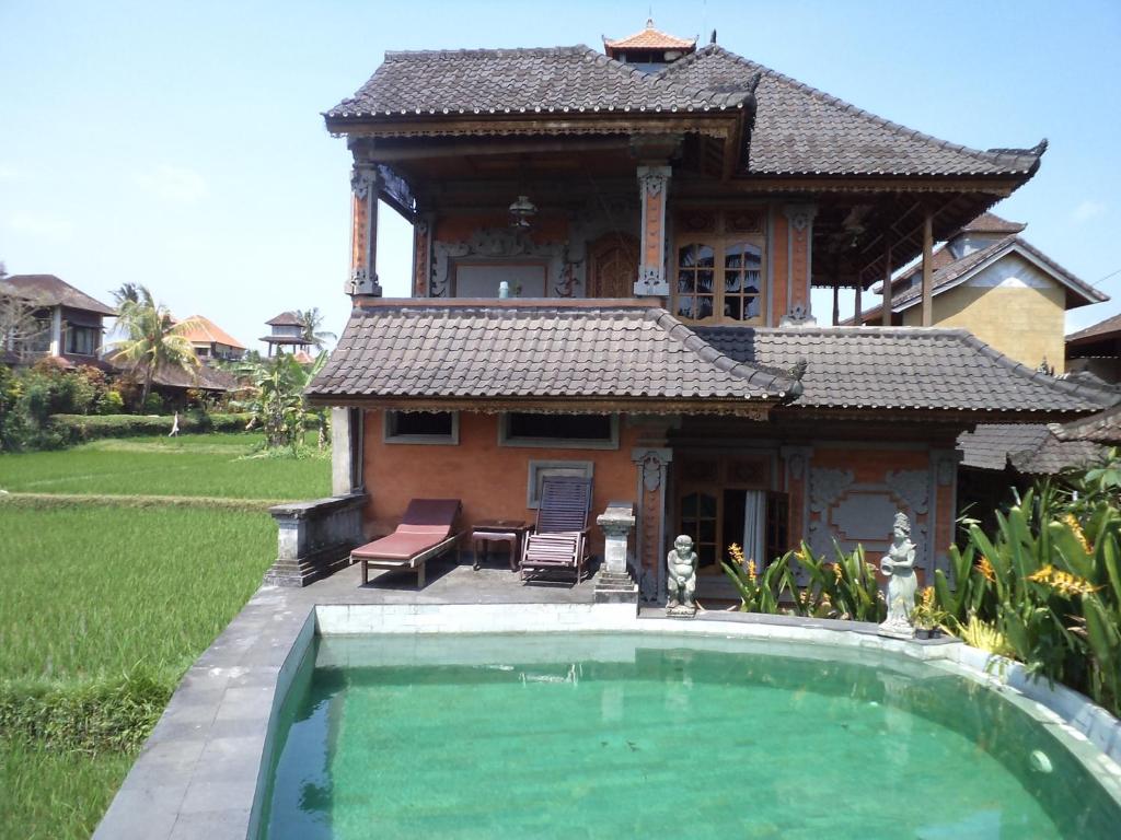 a house with a swimming pool in front of it at Ala's Green Lagoon in Ubud
