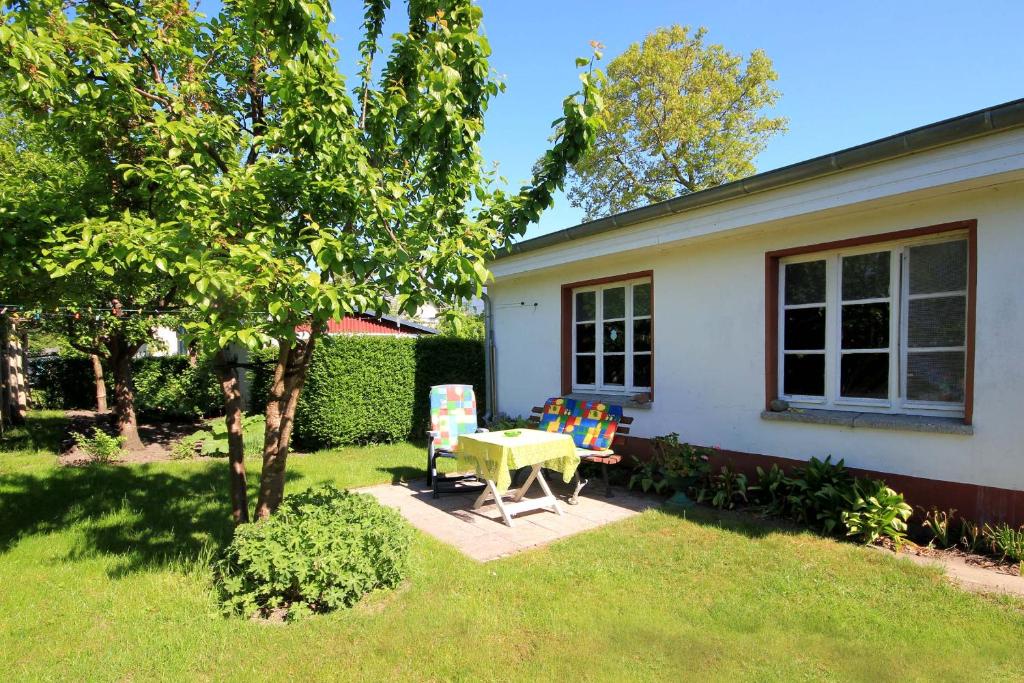 ein Haus mit einem Tisch und einem Stuhl im Hof in der Unterkunft Bungalow am Schmachter See by Rujana in Binz