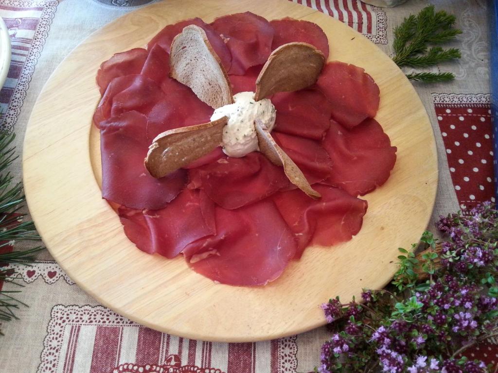 un plato de comida con carne y frutos secos en una mesa en Hotel Corona en Branzi