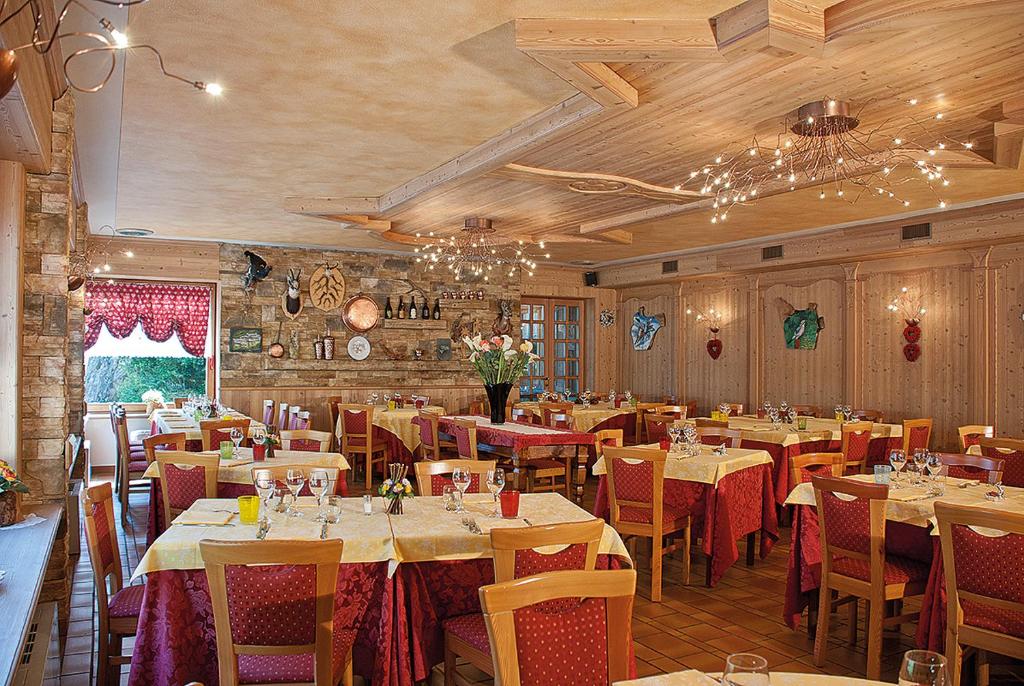 restauracja ze stołami i krzesłami w pokoju w obiekcie Hotel Corona w mieście Branzi