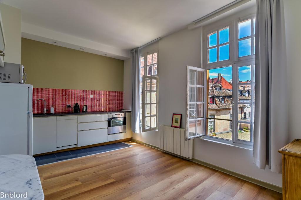 eine Küche mit weißen Schränken und einem großen Fenster in der Unterkunft Bel appartement hypercentre de Strasbourg in Straßburg