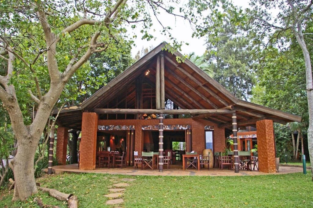 a pavilion with tables and chairs in a park at Phophonyane Falls Ecolodge in Piggs Peak