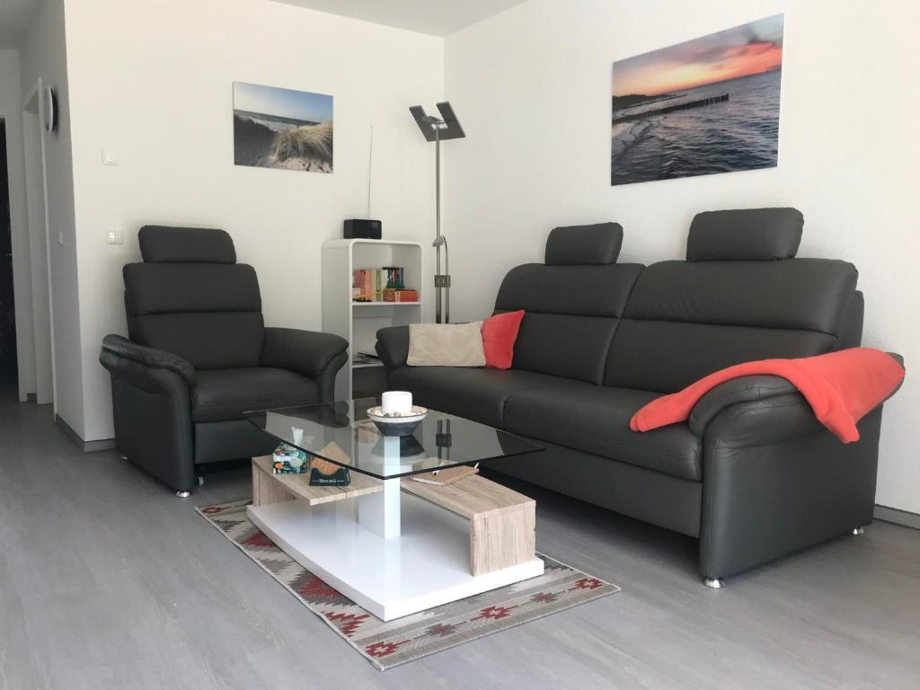 ein Wohnzimmer mit einem schwarzen Sofa und einem Tisch in der Unterkunft Ferienwohnung Zweisamkeit in Graal-Müritz