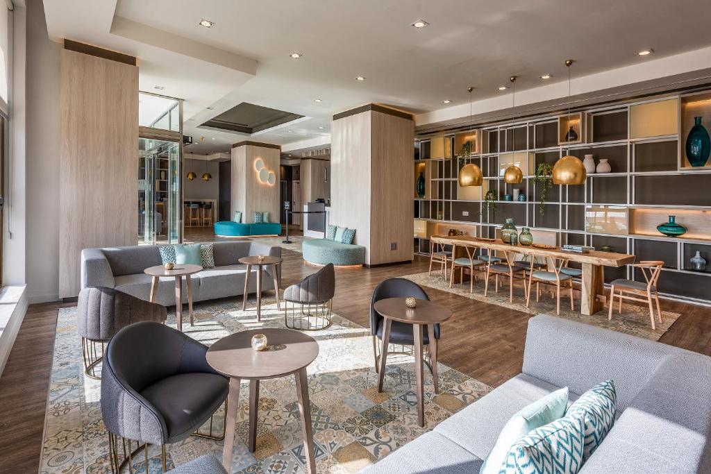 a lobby with couches and tables and chairs at Hotel Cádiz Paseo del Mar, Affiliated by Meliá in Cádiz