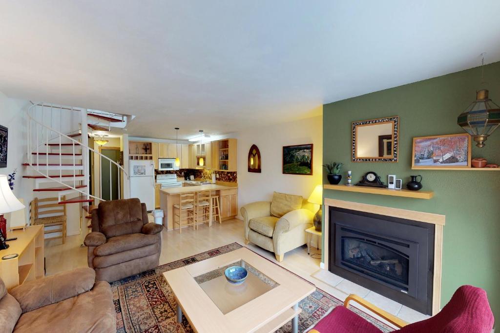 a living room with a fireplace and a kitchen at Brighton Condo #208 in Girdwood