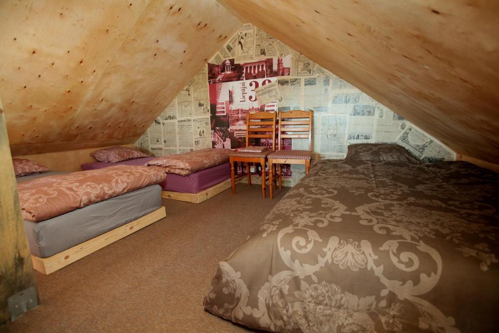 a attic bedroom with two beds and a table at Atomiņi in Aucugals