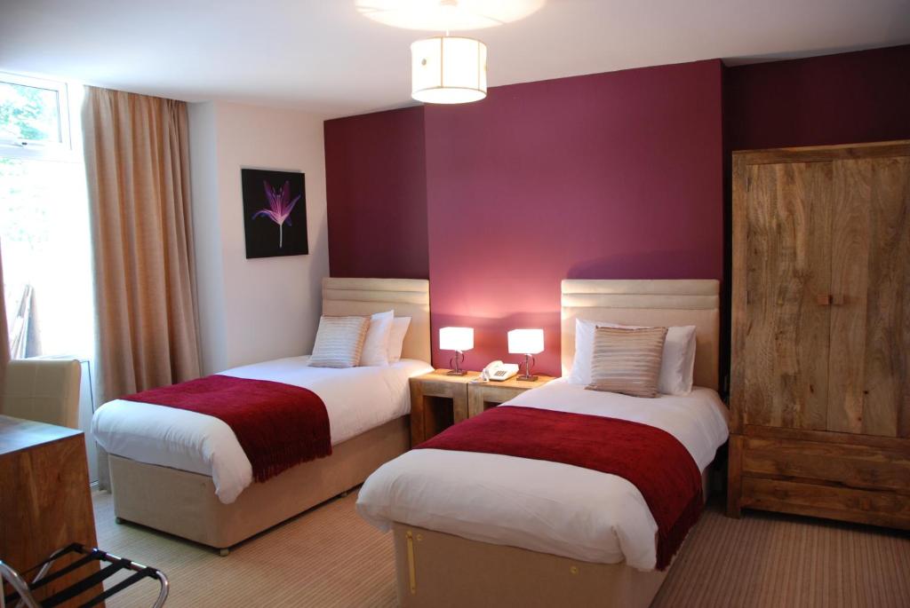 two beds in a hotel room with purple walls at The Port House in Heysham