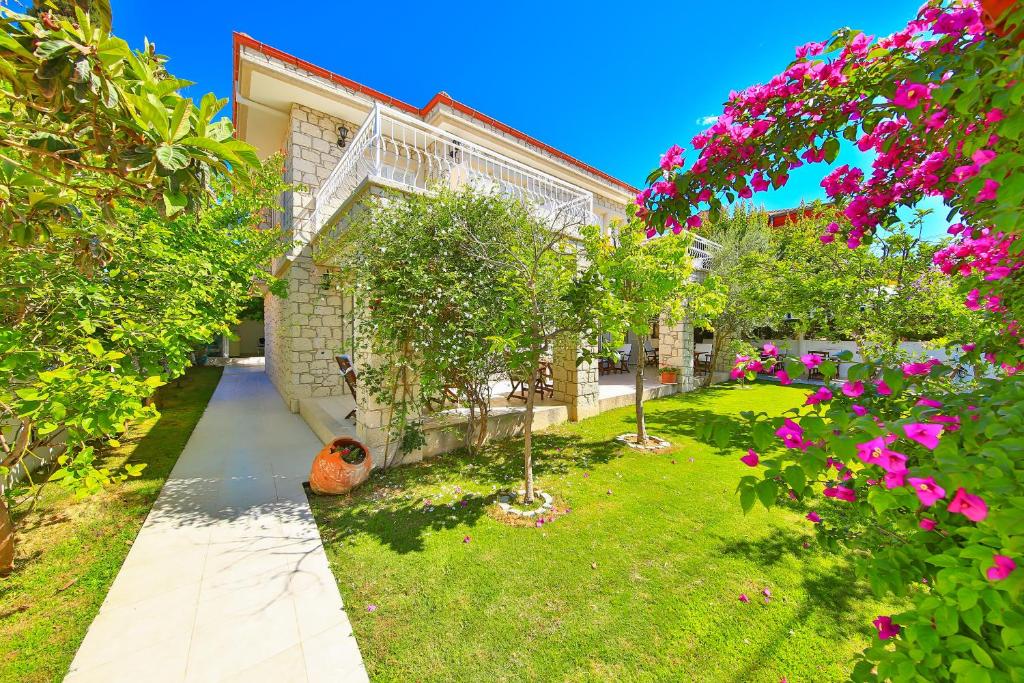 a garden with trees and pink flowers in front of a building at Alacati Sorf Hotel in Alaçatı