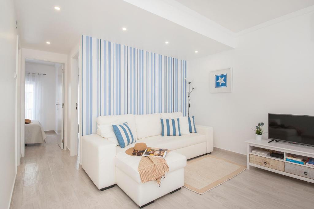 Una sala de estar blanca con un sofá blanco y un televisor. en Ericeira T2 Navegantes Apartment, en Ericeira