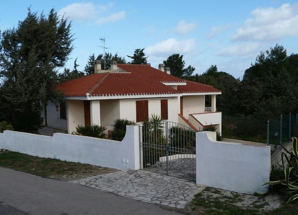 een wit huis met een rood dak en een hek bij Villa Solinas in Sorso